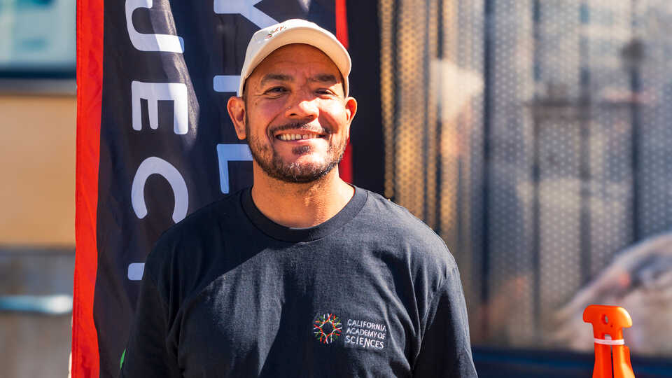 Alvaro Palacios Casanova, Coalition Program Manager at Cal Academy, smiles at a community event in the Tenderloin
