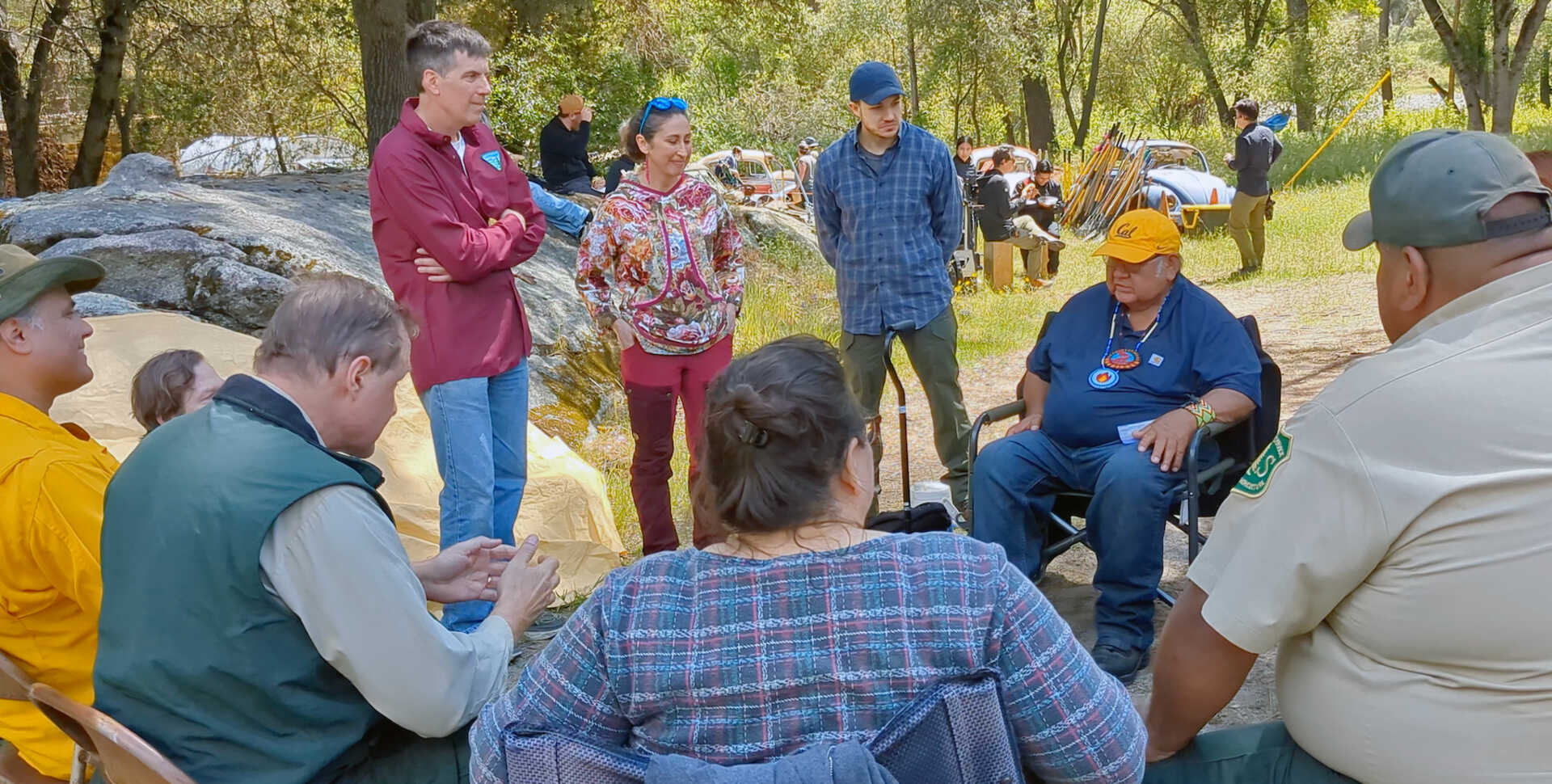 A group of roughly 10 people sit in a circle and discuss intentional fire practices.