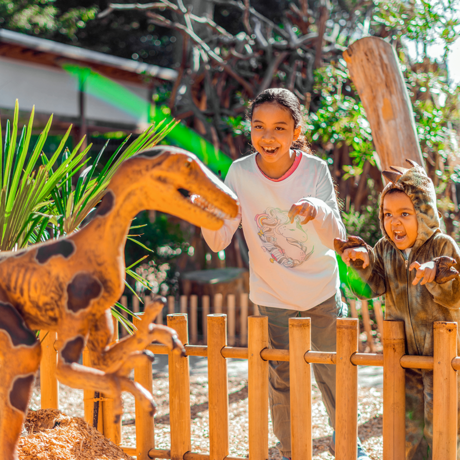 Two children mimicking animatronic dinosaur